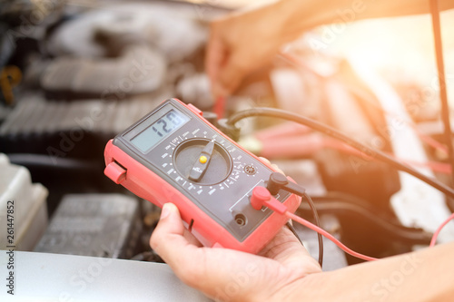 auto mechanic check car battery voltage by voltmeter multimeter photo