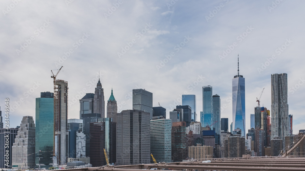 Skyscrapers of downtown Manhattan under clouds and sky viewed from Brooklyn Bridge Park, in Brooklyn, New York, USA