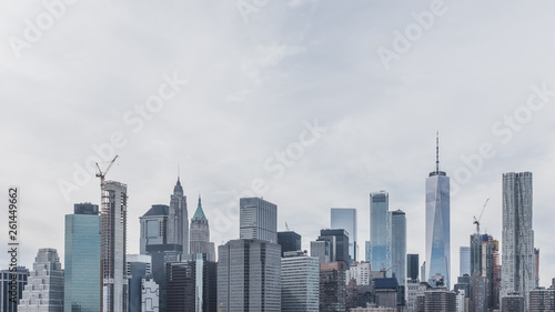 Skyscrapers of downtown Manhattan under clouds and sky viewed from Brooklyn Bridge Park, in Brooklyn, New York, USA
