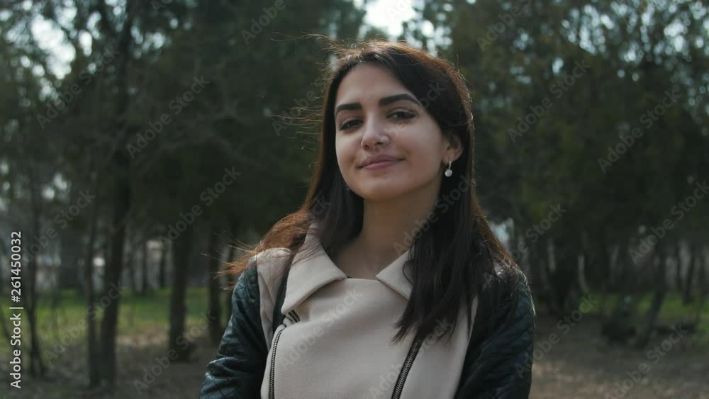 Awesome happy girl looking at camera on the nature background. Young woman smiling in a park Awesome happy girl looking at camera on the nature background. Young woman smiling in a park