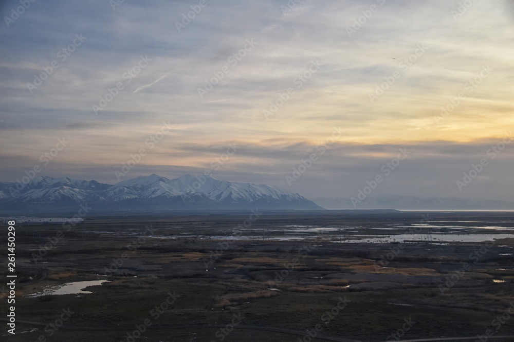 Aerial view from airplane of Antelope Island at sunset, view from Magna, sweeping cloudscape at sunrise with the Great Salt Lake State Park in winter. USA, Utah.