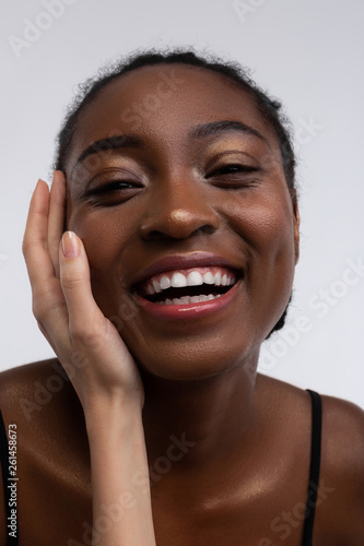 African-American woman smiling while white hand touching her face