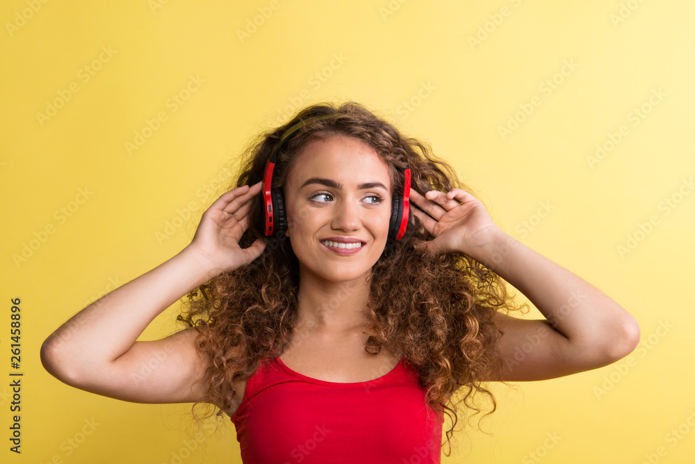 Portrait of a young woman with headphones in a studio on a yellow background. Portrait of a young woman with headphones in a studio on a yellow background.