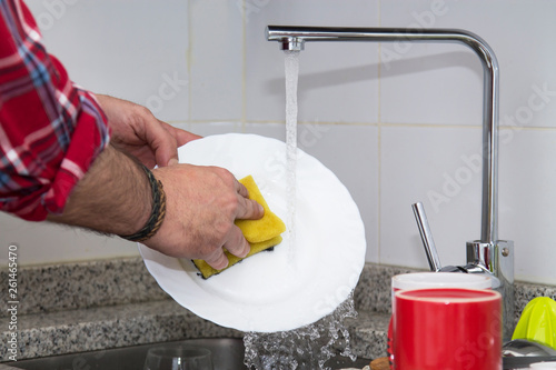 man hand washing dishes over the sink in the kitchen