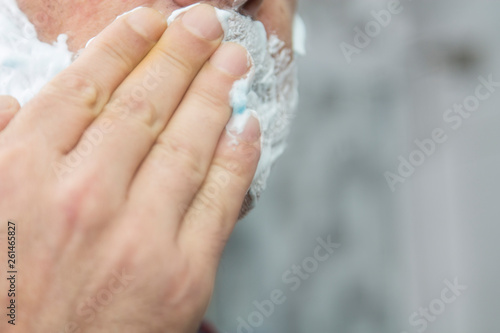 man applying shaving cream on beard