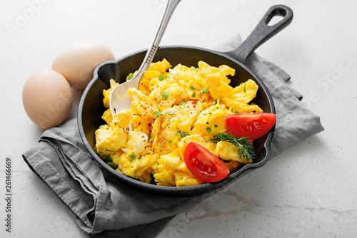 Scrambled eggs on skillet over gray stone background.