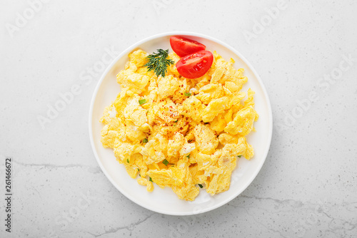 Scrambled eggs on plate over gray stone background.