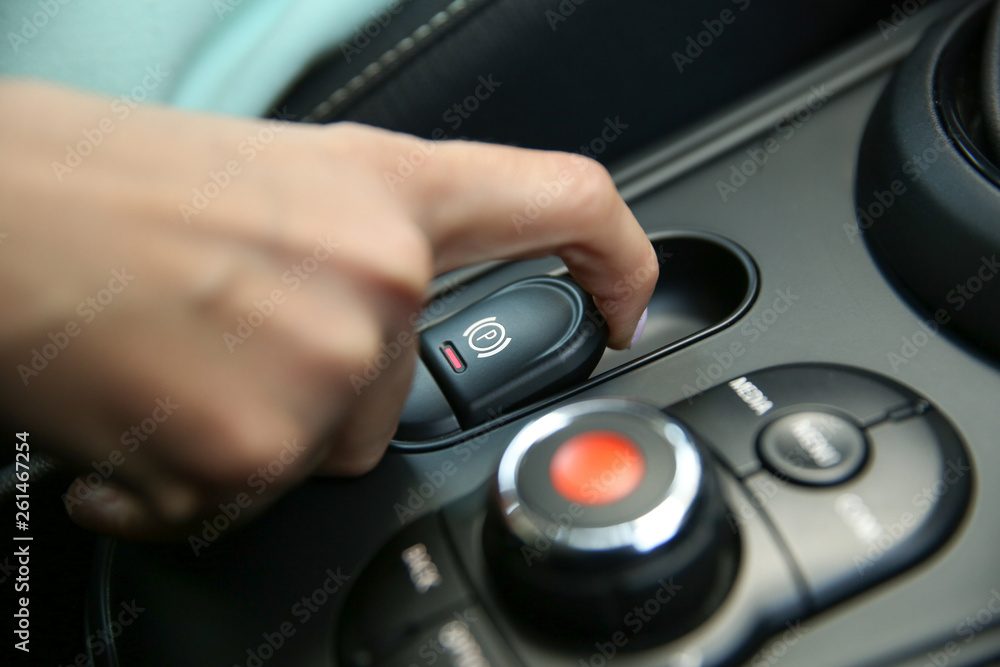 female hand pulls the hand brake button in a modern car. electric hand brake in a car