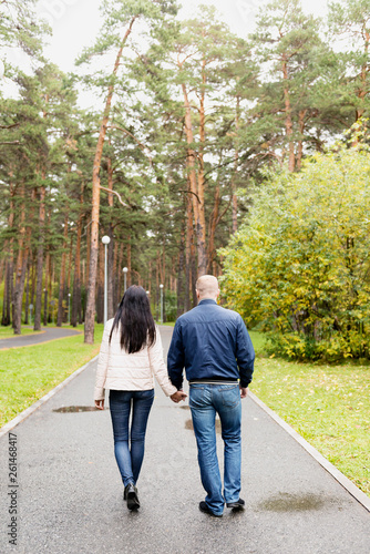 Fototapeta Naklejka Na Ścianę i Meble -  A man and a woman walking down the alley in the Park, holding hands