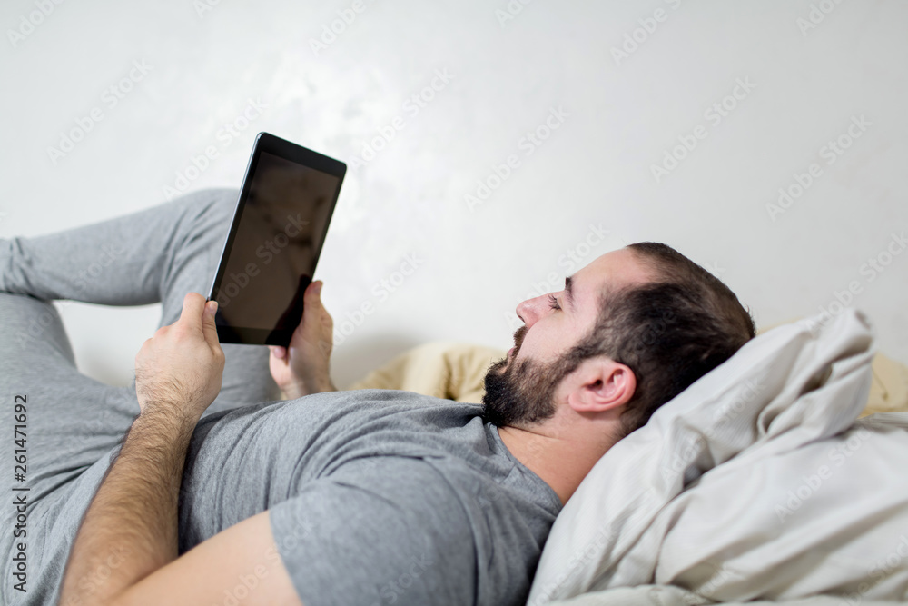 Young and beautiful man holds a tablet in his hands.
