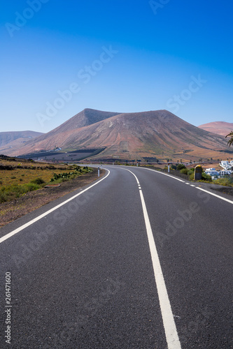 Spain, Lanzarote, Curved black asphalt road through volcanic mountains