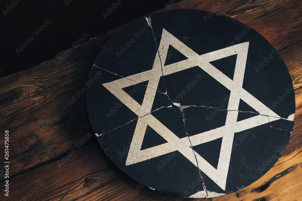 Fototapeta Cracked round stone with a star of David on an old wooden table.