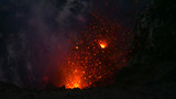 CLOSE UP: Glowing pieces of lava fly up in the air out of an active volcano.