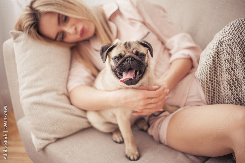 Lovely girl hugging her pug and playing with him in the house Lovely girl hugging her pug and playing with him in the house