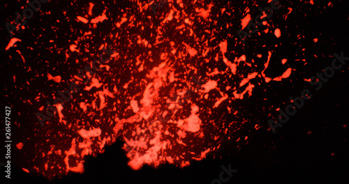 CLOSE UP: Active volcanic crater spewing out pieces of bright orange magma.