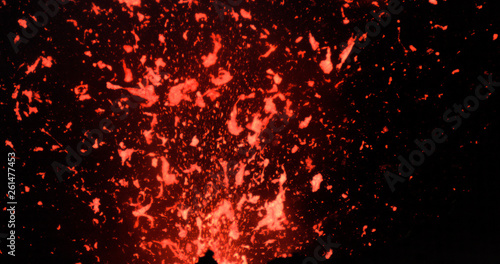 CLOSE UP: Active volcanic crater emitting bright pieces of lava during eruption.