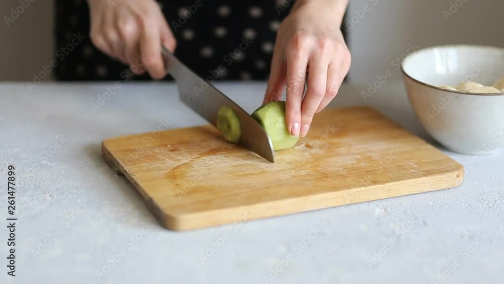 Closeup of a woman cutting with a knife peeled green kiwi. Healthy Breakfast, meals Closeup of a woman cutting with a knife peeled green kiwi. Healthy Breakfast, meals