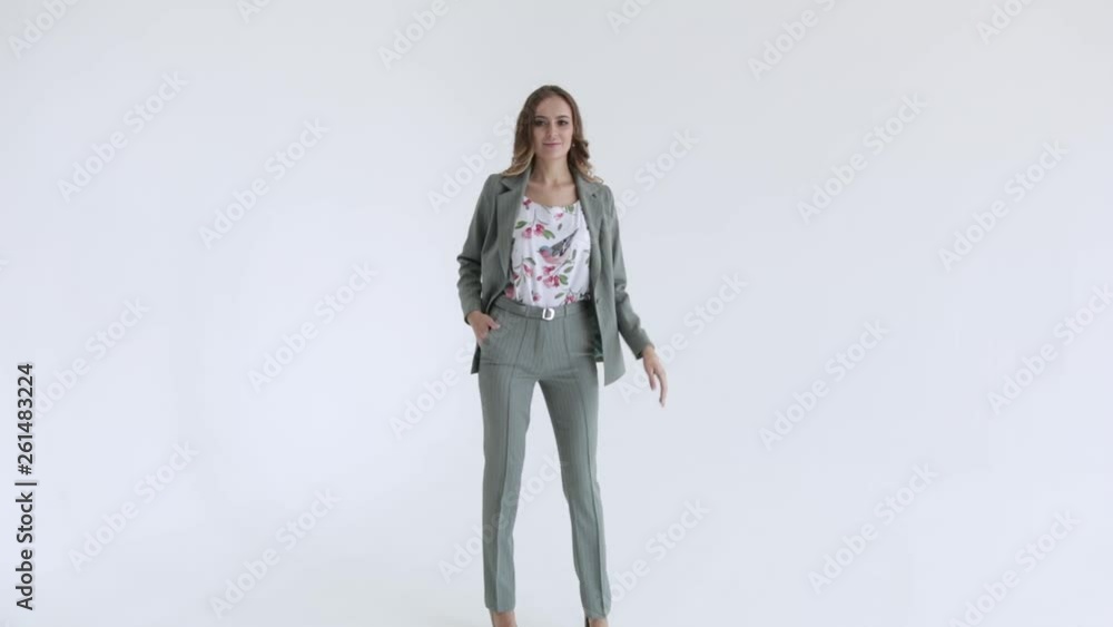 Business lady posing in a gray jacket and trousers on a white background. Sexy female model, in gray suit goes ahead, slow mo