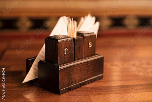 On a wooden table in the cafe there is a wooden box for pepper and salt with letters P and S