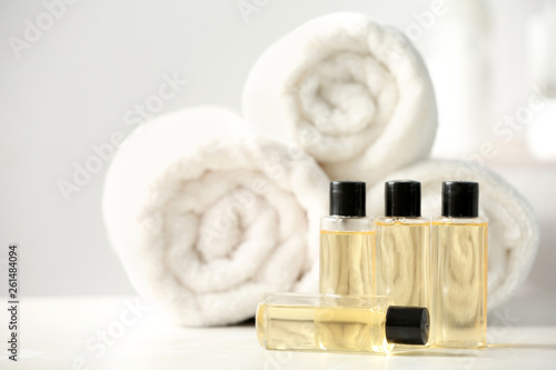 Mini bottles with cosmetic products and towels on table, space for text. Hotel amenities photo