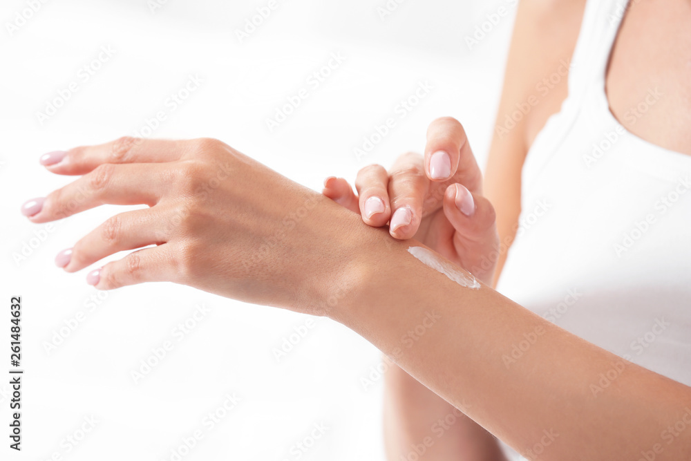 Young woman applying cream on white background, closeup. Beauty and body care