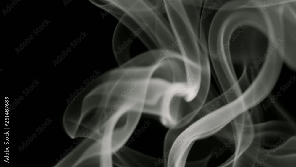 Thin trickle of gray smoke slowly rising graceful twists up on black background. Black and white smoke blowing from bottom to top. Closeup Thin trickle of gray smoke slowly rising graceful twists up on black background. Black and white smoke blowing from bottom to top. Closeup