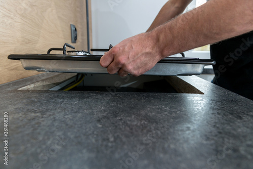 Man installing a gas hob in a kitchen