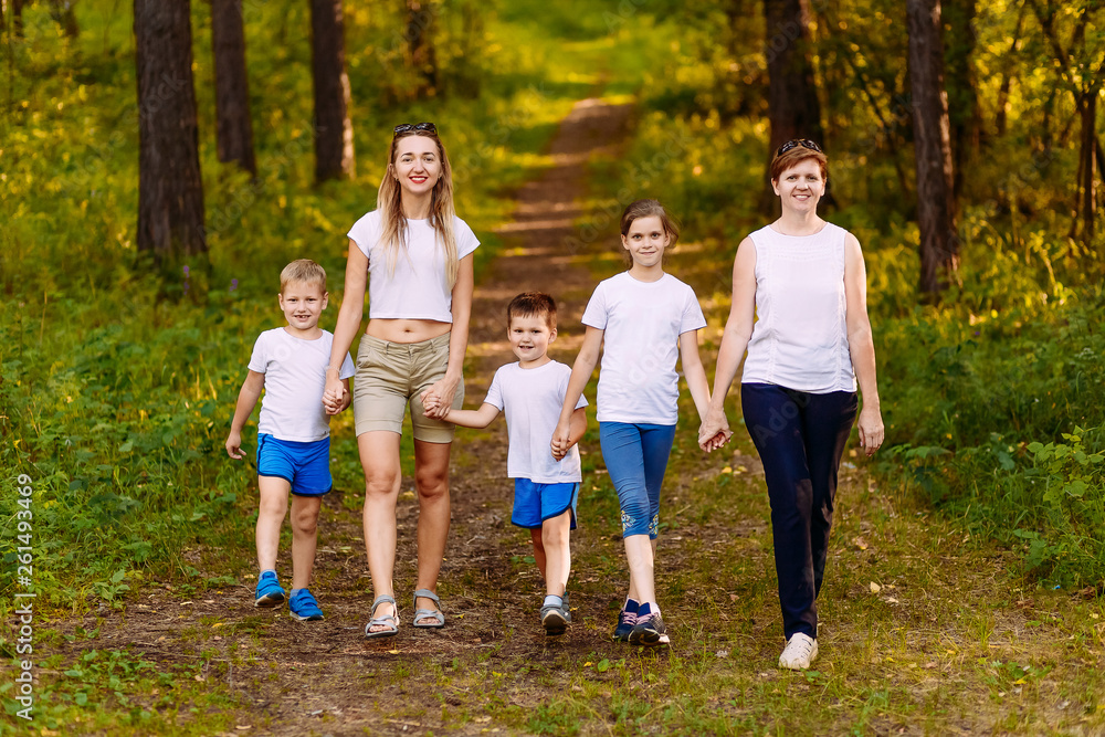 Fototapeta premium smiling mothers and children holding hands. Big happy family, two women and three children in white t-shirts