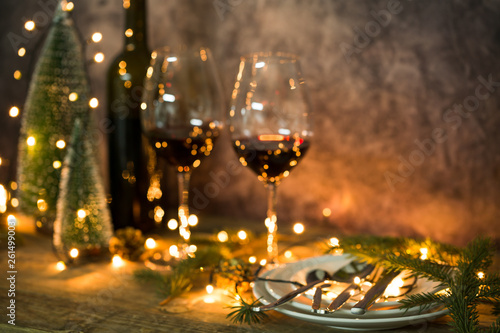 Closeup of red wine on table with Christmas lights. Christmas table and tree.