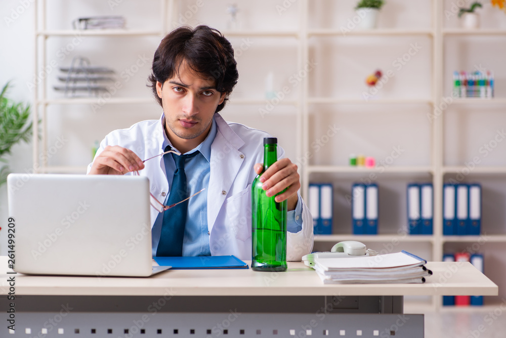 Young male doctor drinking in the office Young male doctor drinking in the office