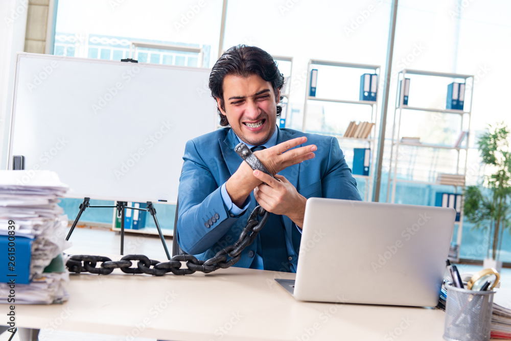 Chained male employee unhappy with excessive work Chained male employee unhappy with excessive work