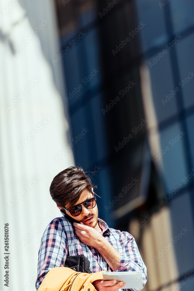 Front view of a happy man calling on the phone walking on the street