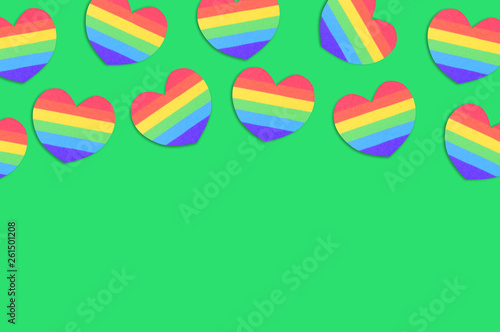 Scattered paper hearts in colors of lgbt flag on green table. Top view. Lgbt rights concept. Copy space for your text