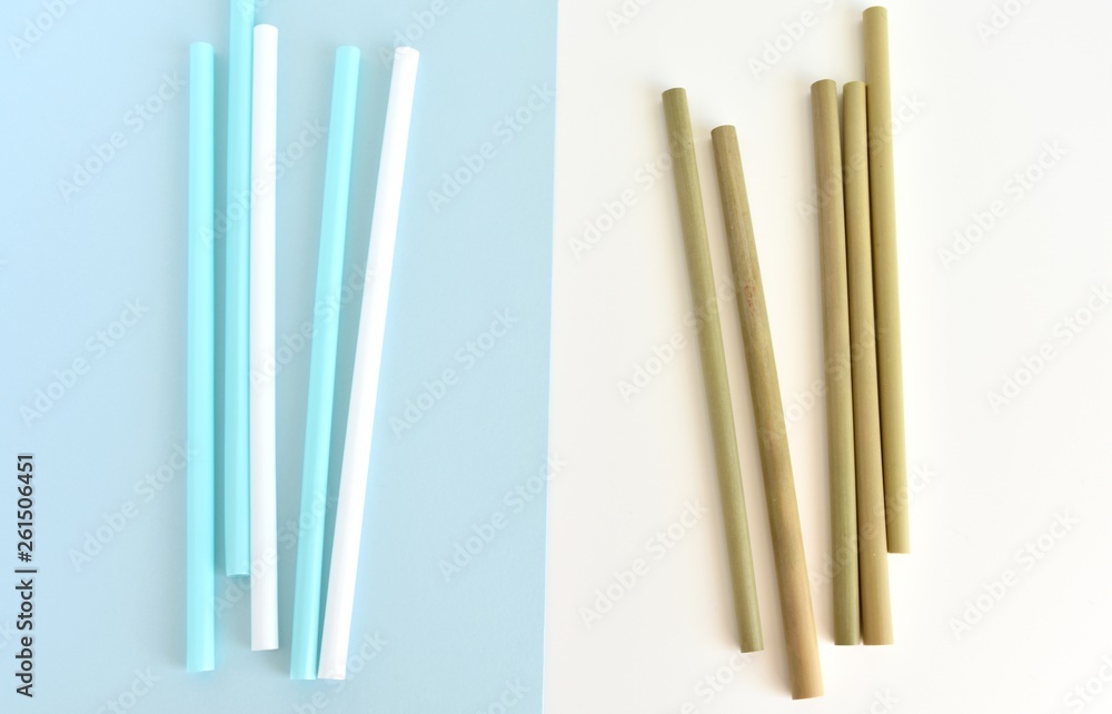 Choice between one time use plastic straw and natural bamboo straw, flat lay on white blue background, zero waste, no plastic concept. Choice between one time use plastic straw and natural bamboo straw, flat lay on white blue background, zero waste, no plastic concept.