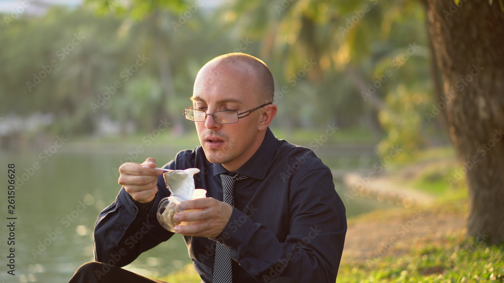 Office Worker Eating Healthy Yoghurt At Park During Sunset Office Worker Eating Healthy Yoghurt At Park During Sunset