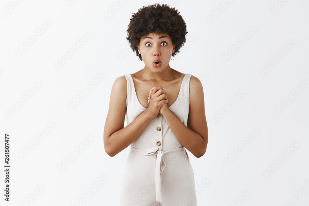 Emotive good-looking woman easy to impress, clenching arms near chest, saying wow with folded lips and popped eyes, being amazed while hearing out exciting and surprising story over grey wall Emotive good-looking woman easy to impress, clenching arms near chest, saying wow with folded lips and popped eyes, being amazed while hearing out exciting and surprising story over grey wall