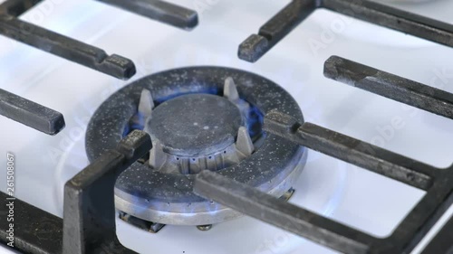 Self-igniting big gas berner turning on the cooktop gas sove. Gas stove with lattice. Close-up view. photo