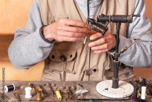 Man making trout flies. Fly tying equipment and material for fly fishing preparation .