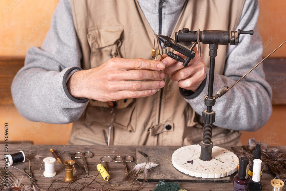 Fototapeta premium Man making trout flies. Fly tying equipment and material for fly fishing preparation .