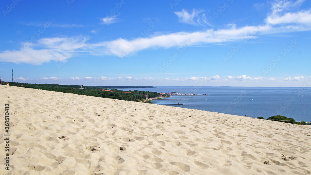 Sandy beach and dunes near the sea and bright blue sky. Sunny summer day.