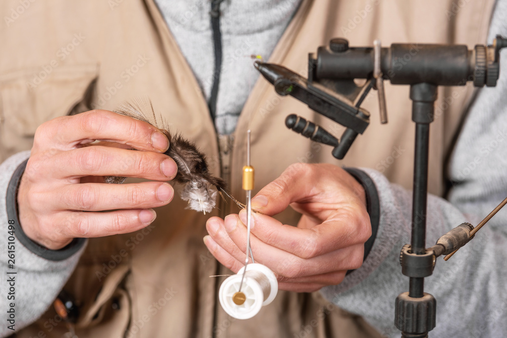 Fototapeta premium Man making trout flies. Fly tying equipment and material for fly fishing preparation .
