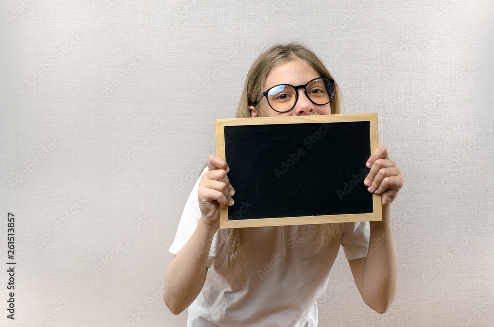 Beautiful mischievous girl with glasses holding a sign in her hands. copy-space Beautiful mischievous girl with glasses holding a sign in her hands. copy-space