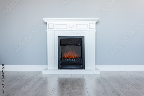 White wooden decorative electric fireplace with a beautiful burning flame. Interior photo on gray background.