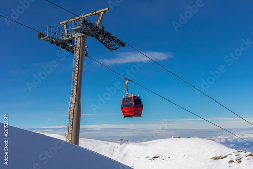 A red cable car cabin in the winter sports region at Granada in the Sierra Navada in front of blue sky with clouds photo