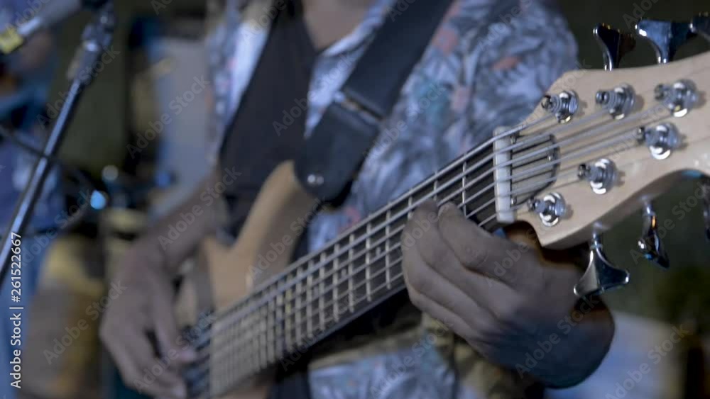 Close up of a Bass player in a band playing a 6 string bass guitar