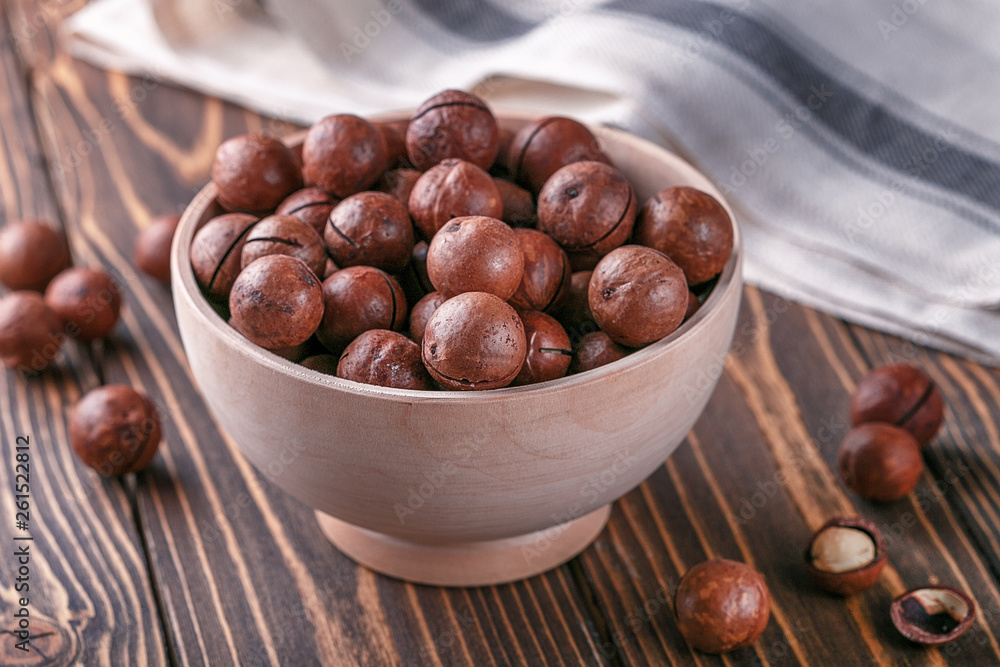 macadamia nuts in wooden bowl on wooden ructic surface. macadamia nuts in wooden bowl on wooden ructic surface.