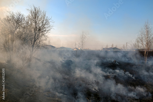 The grass is Burning near houses, danger of fire, ignition.
