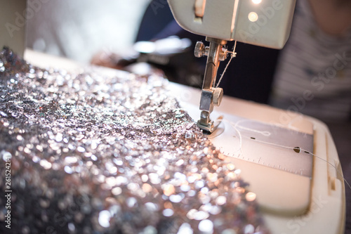 Close-up photo of sewing machine with shiny piece of fabric. Prom dress preparation. Fashion design concept photo