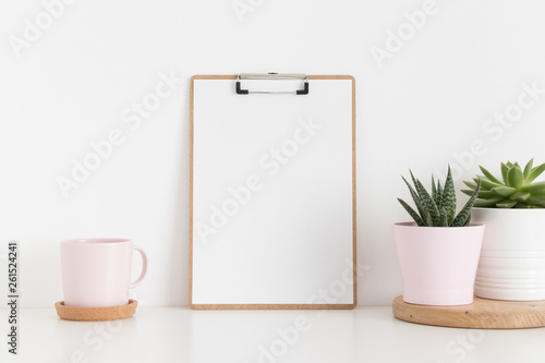 Wooden clipboard mockup with various types of succulents and a cup on a white table.