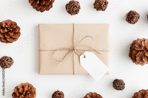 Top view of a kraft christmas gift with a blank tag surrounded with pine cones.